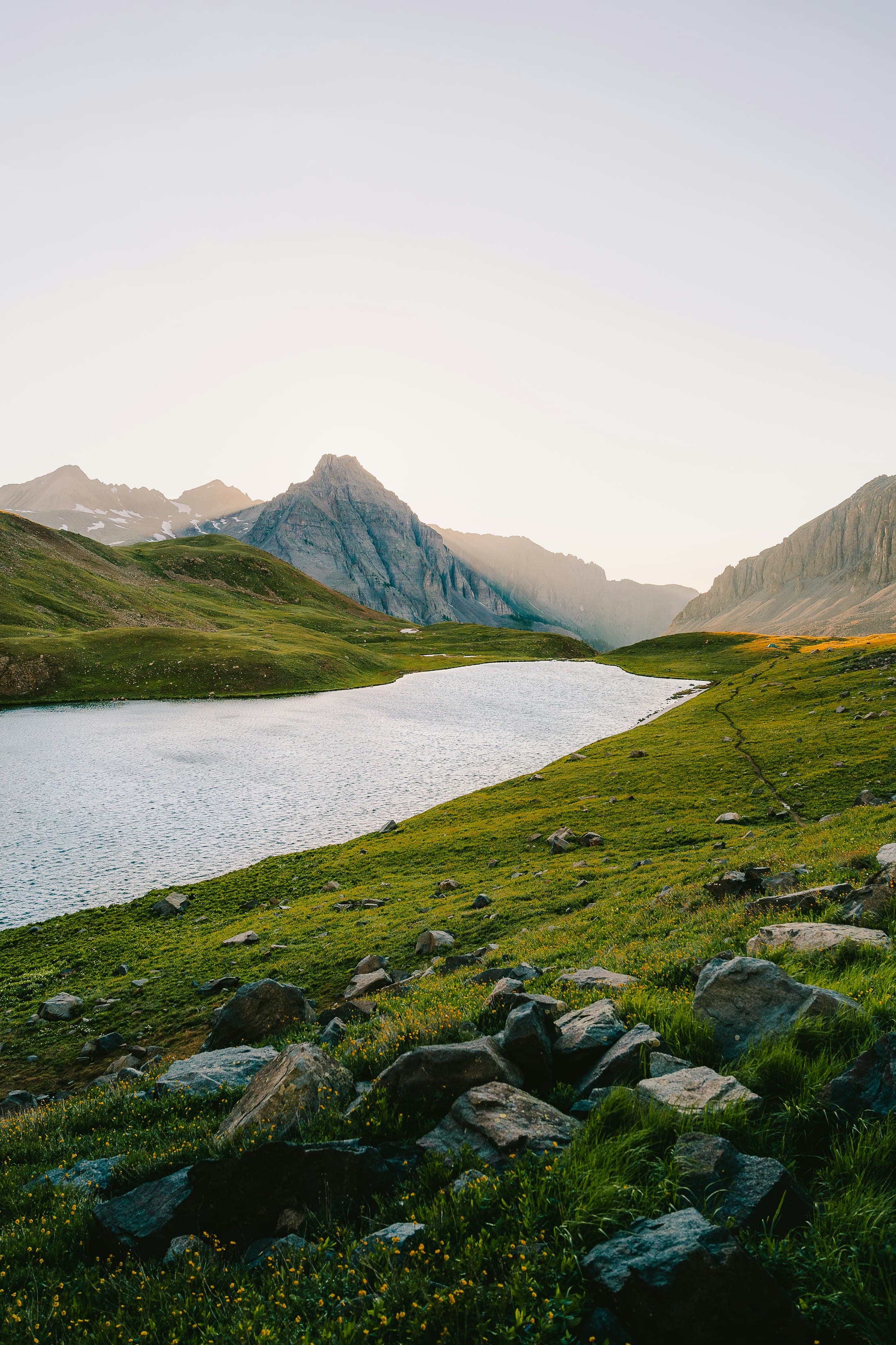 Bergsee und grüne Almwiesen vor den Gipfeln der Dolomiten