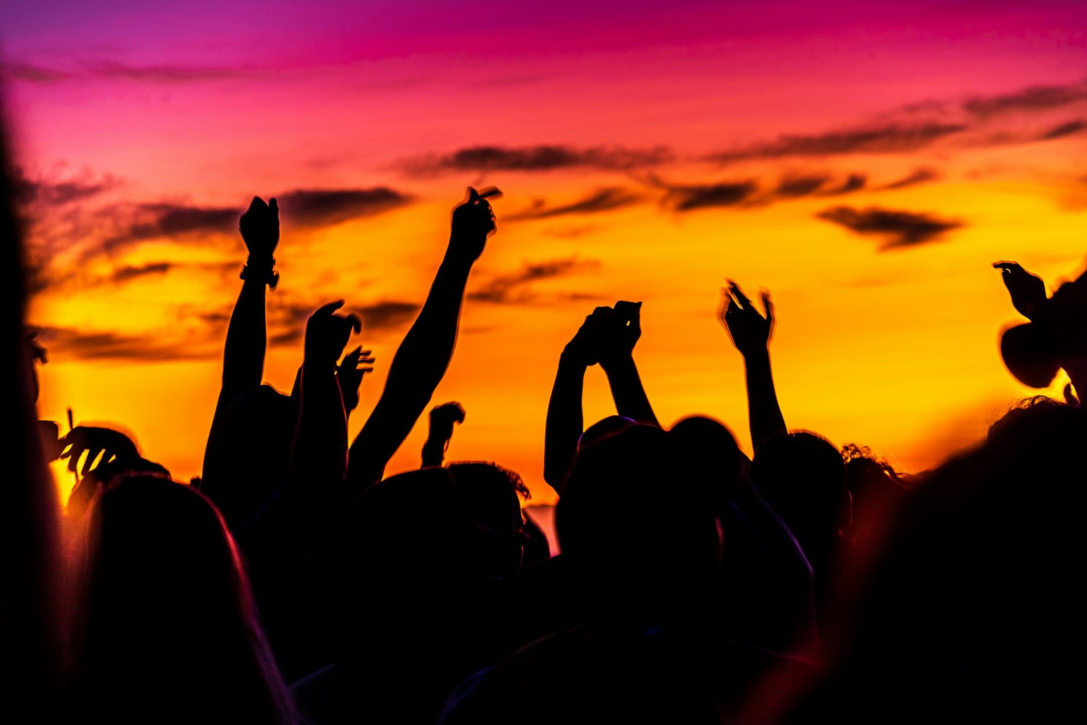 Silhouetten tanzender Gäste vor einem glühenden Sonnenaufgang