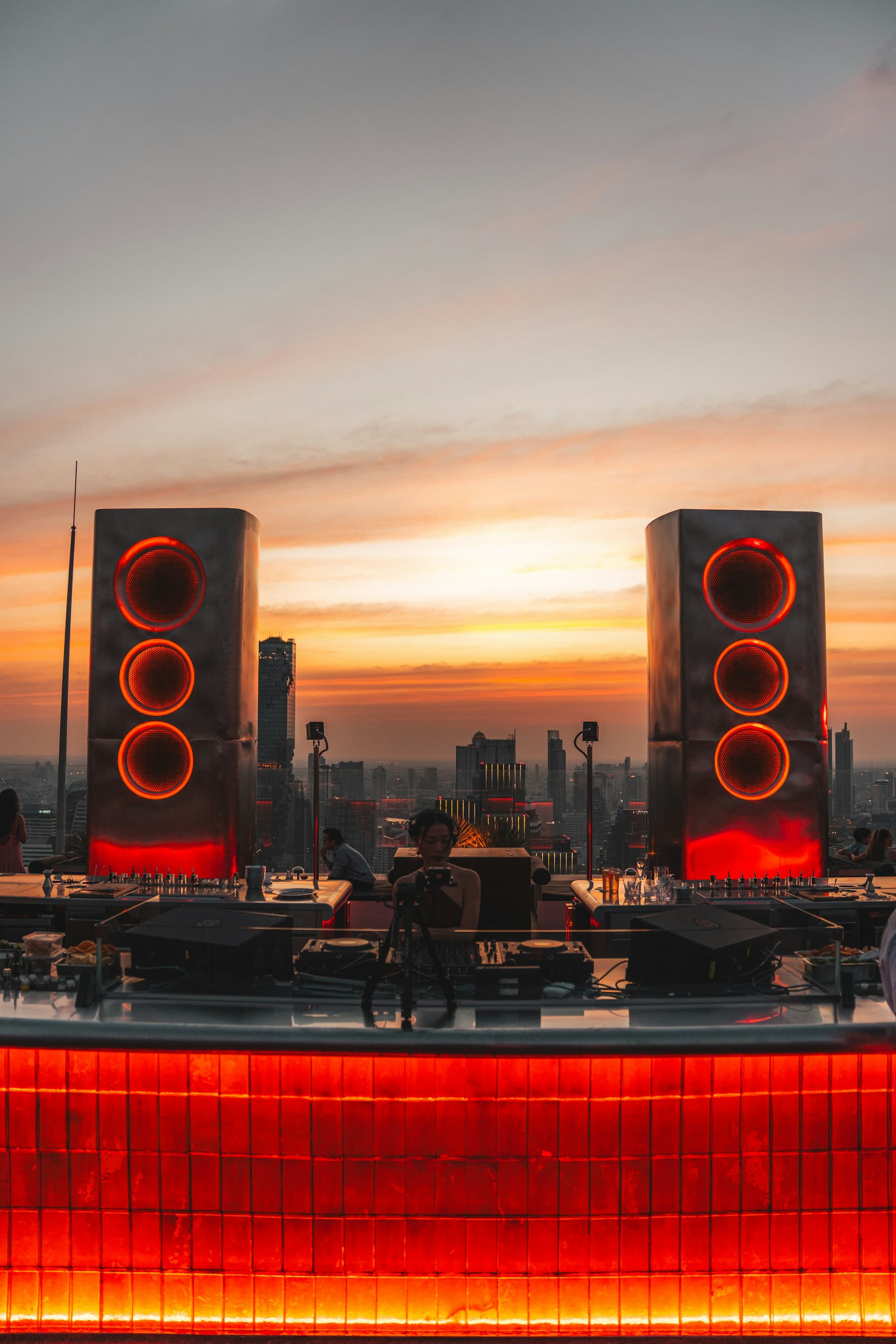 DJ-Pult mit rot leuchtenden Lautsprechern über der Skyline bei Sonnenaufgang